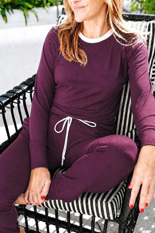 Woman wearing a purple outfit sitting on a black and white striped chair.
